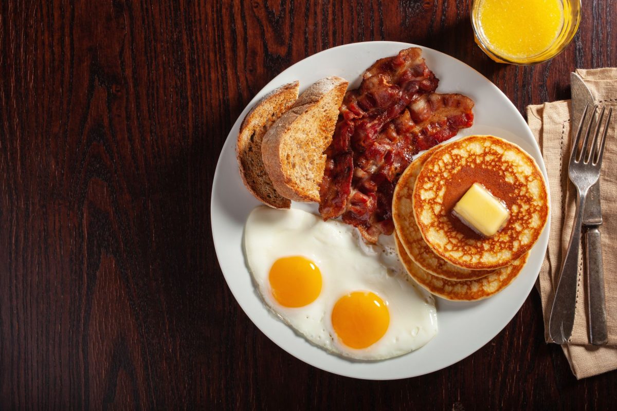 Breakfast plate of pancakes, bacon, eggs, and toast